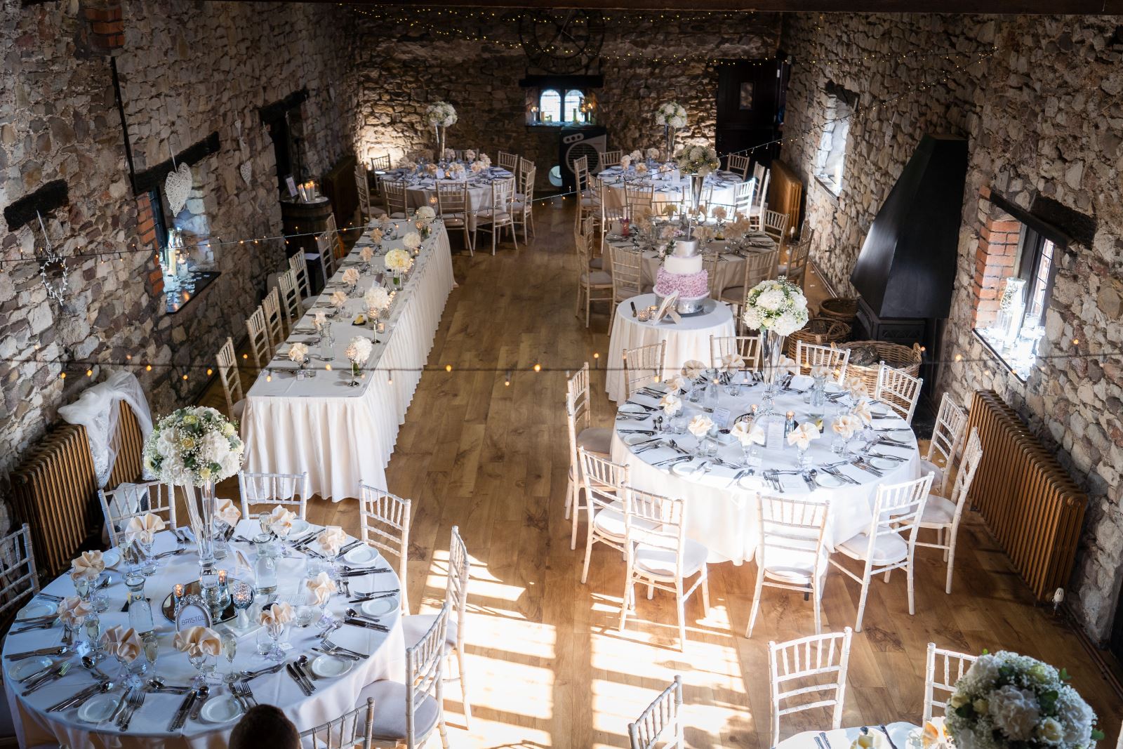 The main space at Pencoed Hall, a big stone barn, photographed from above with the room set up for a wedding breakfast.