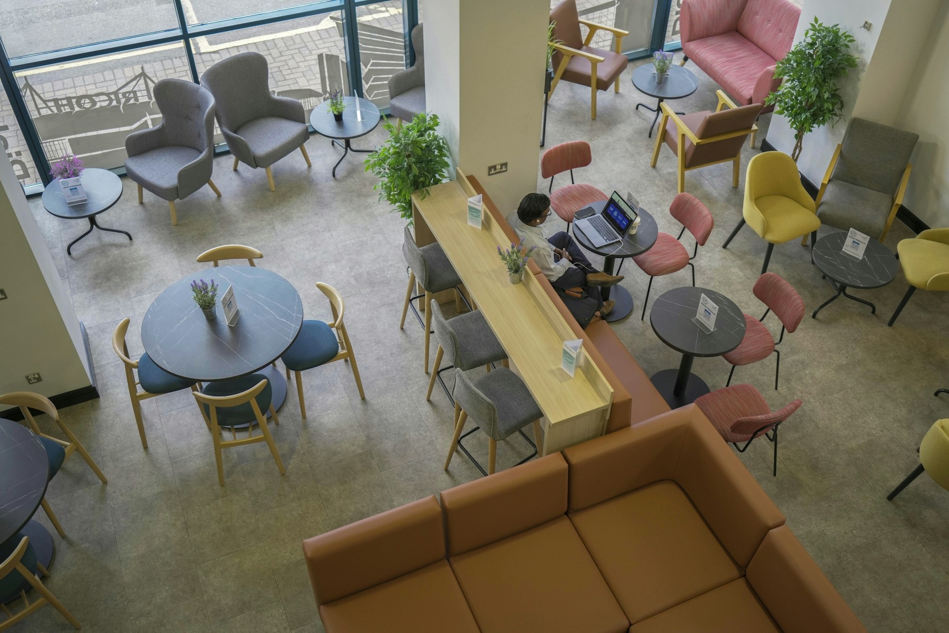 Aerial view of a cafe space with colourful armchairs, chairs, barstools, sofas and tables.