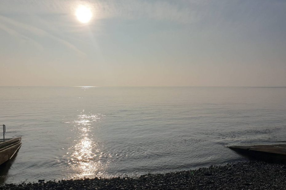 Looking out to sea at Penarth, the sun is reflected on the tranquil water.
