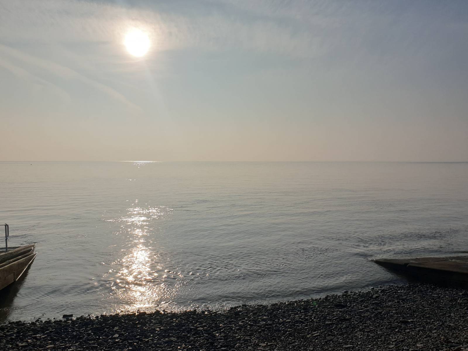 Looking out to sea at Penarth, the sun is reflected on the tranquil water.