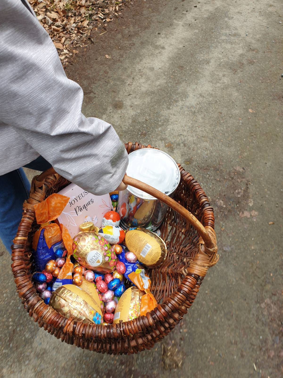 Someone (my friend) is carrying a large wicker basket - you can just see their arm and the basket - which is filled with fancy Easter chocolate eggs of all sizes.